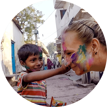 Ein kleines Kind darf Toma Kubiliutes Gesicht mit Fingerfarben bemalen, die gehörlose Reisende und das Kind lächeln.